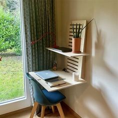 a computer desk with a laptop on it in front of a large window and grass outside