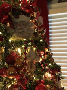 a christmas tree decorated with ornaments and santa claus's head on top is lit up