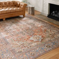 a living room area with a couch, fireplace and rug on the hardwood flooring