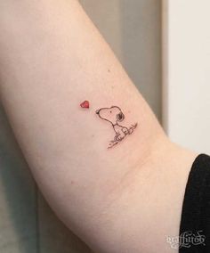 a small dog with a heart tattoo on the arm