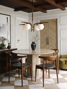 a dining room table with four chairs and a vase on the centerpiece in front of it