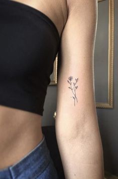 a woman's arm with a small flower tattoo on the left side of her arm