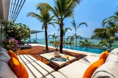 an outdoor living area with couches, tables and palm trees in front of the pool