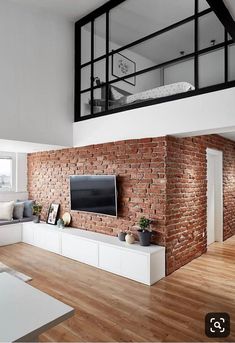 a living room with a brick wall and wooden flooring in the center is an entertainment area