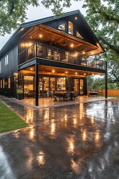 a large house sitting on top of a wet parking lot next to a lush green field