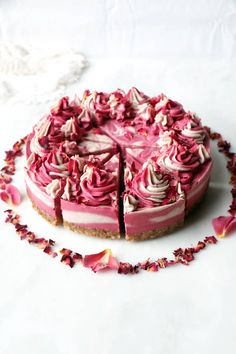 a cake with pink frosting and rose petals on the side is cut in half