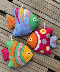 three brightly colored fish ornaments are sitting on a bench