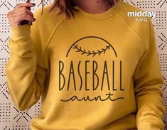 a woman wearing a baseball mom sweatshirt holding a pair of glasses in front of her face