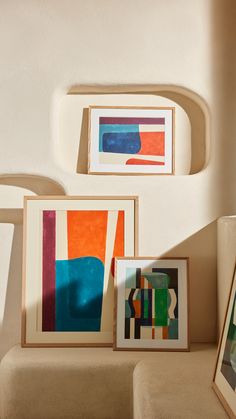 three framed art pieces sitting on top of a table