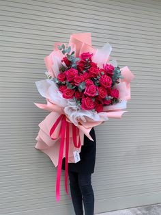 a woman holding a large bouquet of red roses