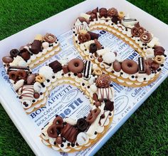 a number shaped cake sitting on top of a white tray covered in chocolate and pretzels