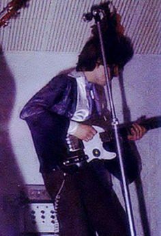 a man playing an electric guitar while standing in front of a microphone and sound equipment