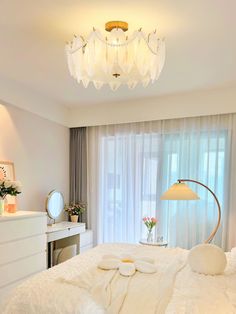 a bedroom with white bedding and a chandelier hanging from it's ceiling