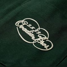 the back of a green polo shirt with an embroidered logo on it