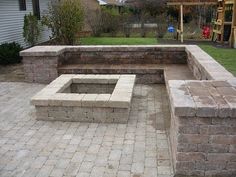 a brick fire pit sitting in the middle of a yard