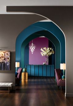 an archway in a living room with purple and teal walls, wood floors and chandeliers