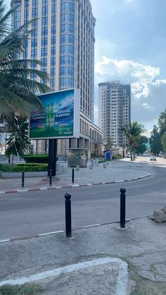 an empty city street with tall buildings in the back ground and palm trees on either side