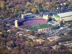 an aerial view of a football stadium in the middle of a city with trees surrounding it