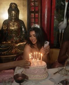 a woman sitting in front of a cake with candles on it and taking a selfie