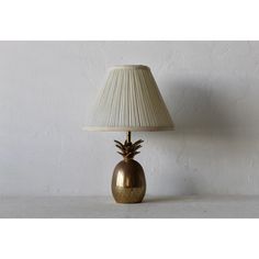 a gold pineapple lamp sitting on top of a table next to a white wall