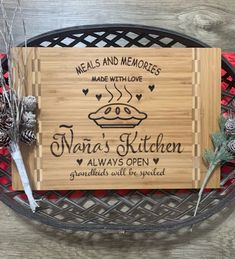 a wooden sign that reads meals and memories made with love, nana's kitchen always open surrounded by pine cones