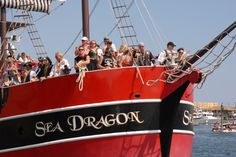 a large group of people on the back of a red and black boat in the water