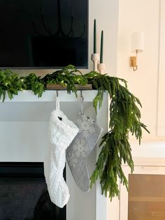 stockings hanging from a mantel decorated with greenery