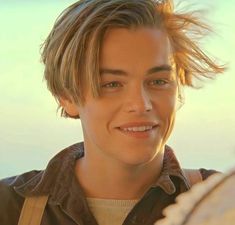 a young man with blonde hair smiling at the camera