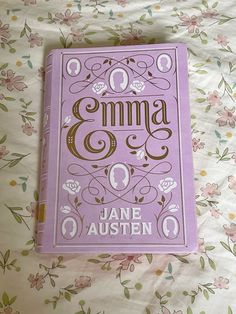 a purple book sitting on top of a bed next to a flowery blanket and pillow