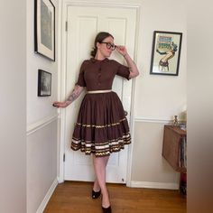 This is a gorgeous 1950s Vintage handmade patio / rodeo / line dancing set.  Two pieces, it is made of a brown cotton material. The top has 3/4 length sleeves and buttons down the front with a slight collar at the neck. The sleeves are frilly / fluttered at the end with gold Rickrack zig-jagged trim.  The skirt is full and tiered and banded at the waist with a gold ribbon. The same metallic Rickrack trim is along the edges of each of the tiers.  Set is modeled wearing a crinoline. The skirt hook Western Patio, Vintage Patio, Womens Suits, Western Vintage, Line Dance, 50s Vintage, Line Dancing, Gold Ribbon, Gold Ribbons