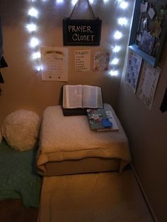 a small bed with a book on top of it and some lights above the headboard