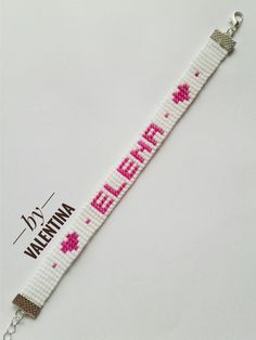 a white bracelet with pink flowers and the word elear on it's side