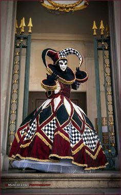 a woman in a costume is standing on the steps with her hands up and wearing a mask