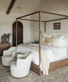 a bedroom with a four poster bed, white furniture and rugs on the floor