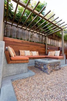 an outdoor seating area with fire pit and wooden pergolated roof over graveled patio