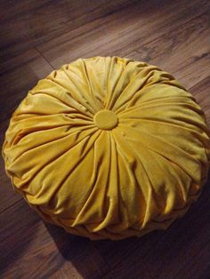 a yellow round pillow sitting on top of a wooden floor