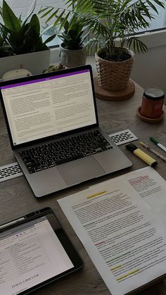 an open laptop computer sitting on top of a wooden desk next to a tablet pc