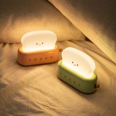 two toaster shaped lights sitting on top of a white bed next to each other