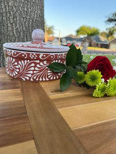 a red and white box sitting on top of a wooden table next to some flowers