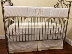 a metal crib with white sheets and blue monogrammed bedding