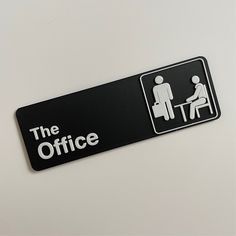 the office sign is black and white with an image of two people sitting at a table