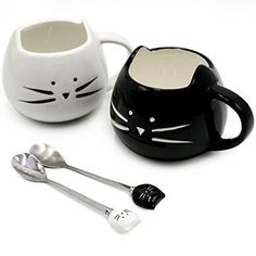 two black and white cat mugs with spoons next to each other on a white surface