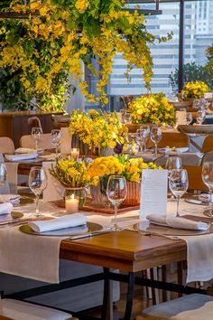 a table set with yellow flowers and place settings for an event or function in a restaurant