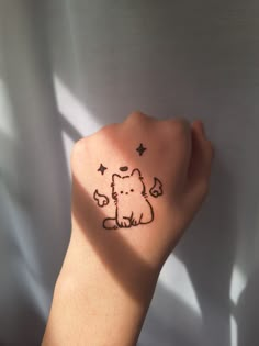 a person's hand with a small dog tattoo on the left side of their arm