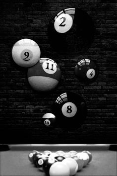 several billiards and eight ball balls on a pool table in front of a brick wall