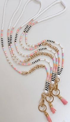 multicolored beaded necklace with tassels and gold tone metal charms on white background