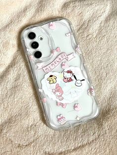 an iphone case with hello kitty and friends on it sitting on a white sheeted surface