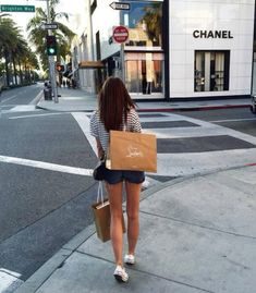 a woman is walking down the street with shopping bags in her hand and she is holding a bag