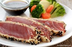 two pieces of tuna on a plate with broccoli and carrots in the background