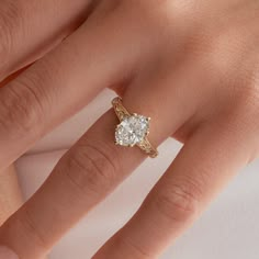 a woman's hand with a diamond ring on top of her finger and the other hand holding an engagement ring